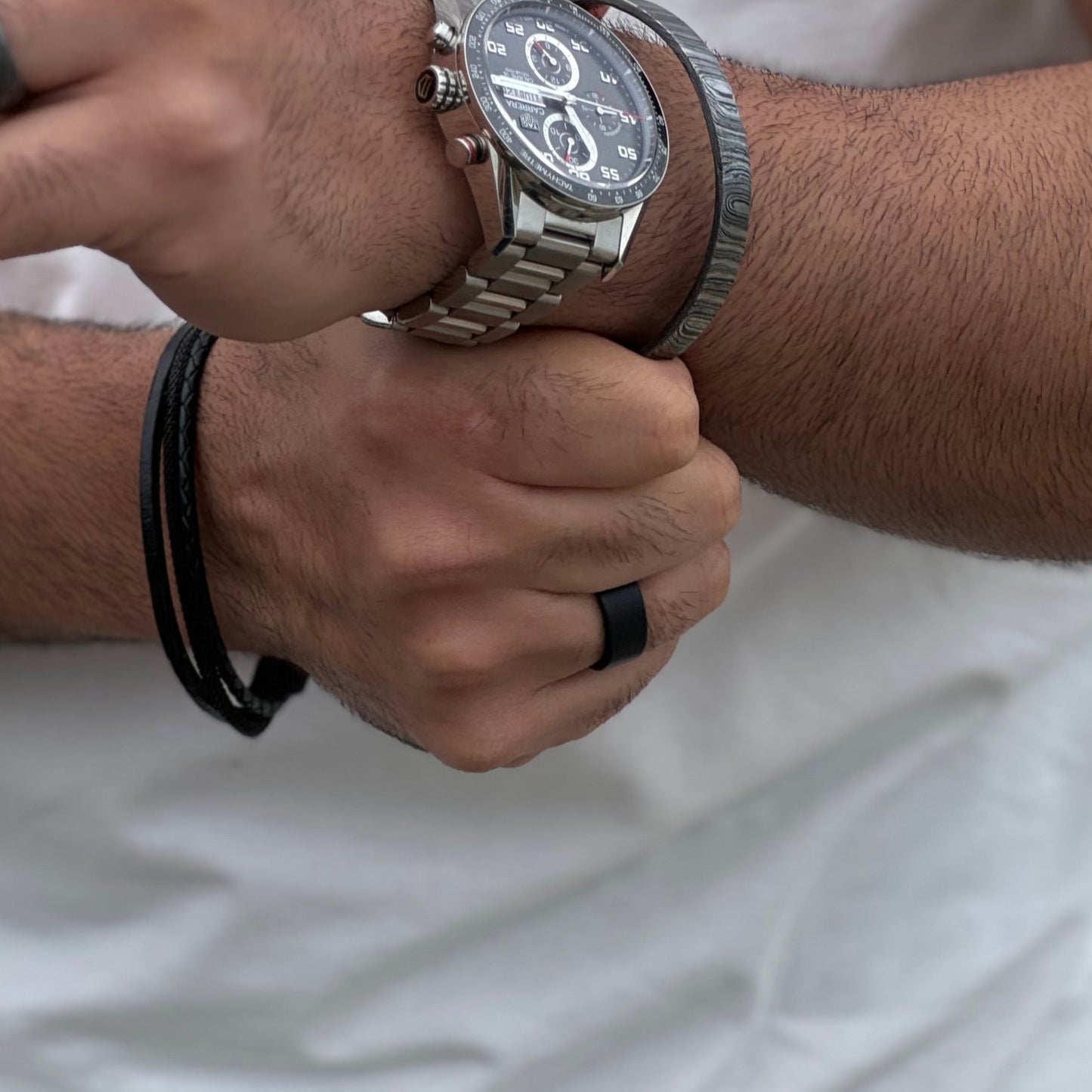 Man wearing back ring with damascus steel bracelet and watch