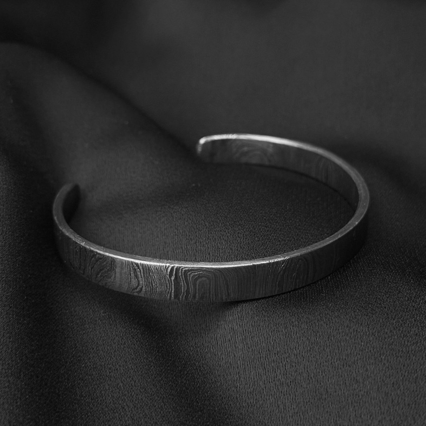 Damascus steel cuff on silk black background