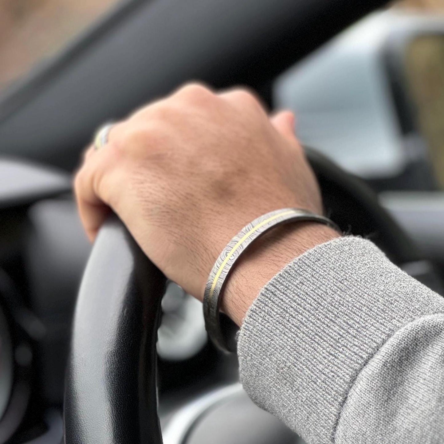 Man wearind Damascus and Brass bracelet while driving