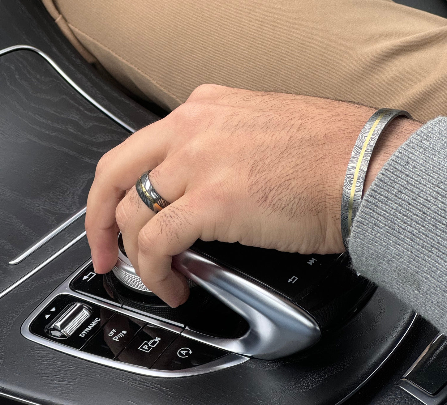 Man wearing Damascus and Brass ring and cuff in mercedes car