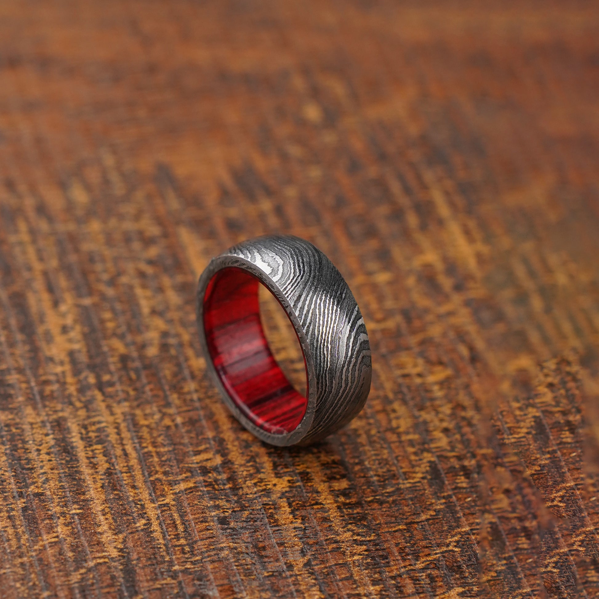 red wood damascus ring on wooden background